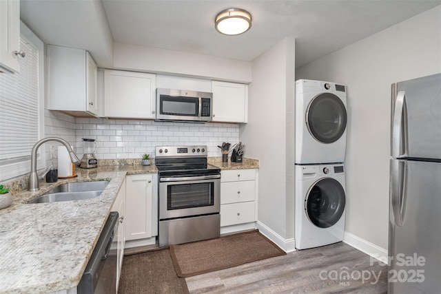1512 Seigle Ave Unit 2, Charlotte, NC 28205 - kitchen with appliances with stainless steel finishes, stacked washing machine and dryer, a sink, baseboards, and white cabinets