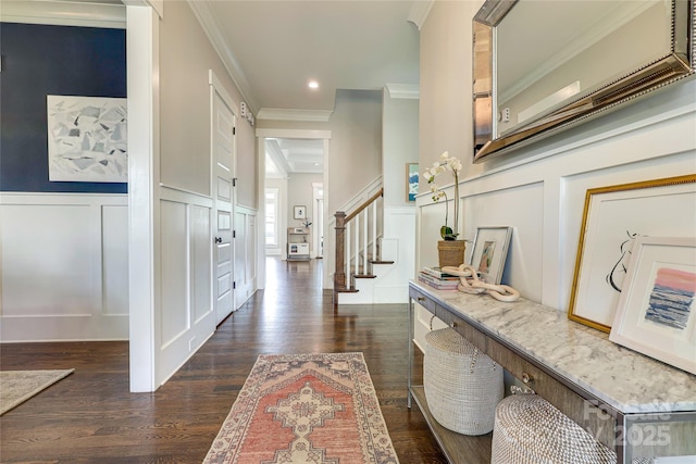 entryway with stairs, ornamental molding, a decorative wall, and dark wood-style floors