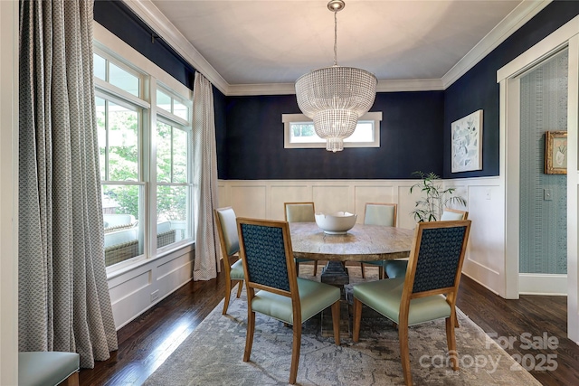 dining space with an inviting chandelier, wood finished floors, a decorative wall, wainscoting, and ornamental molding