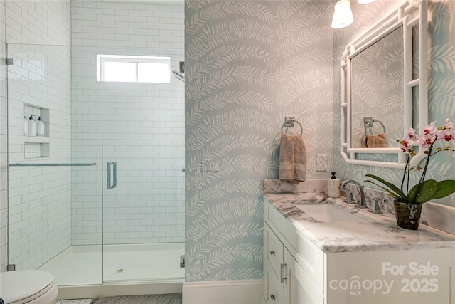 bathroom featuring a stall shower, vanity, toilet, and wallpapered walls