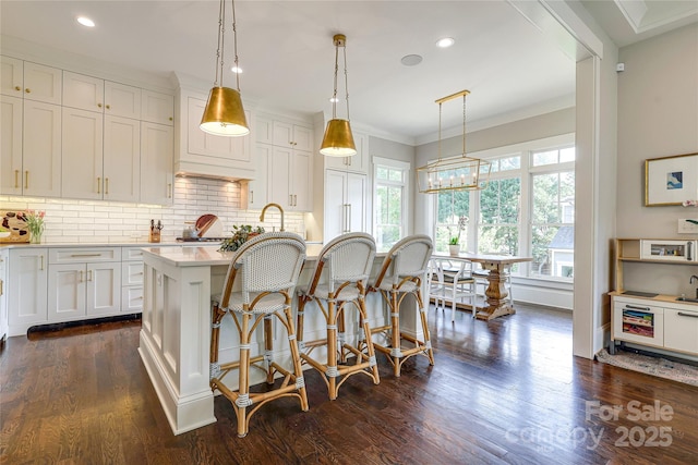 kitchen with light countertops, a wealth of natural light, a kitchen breakfast bar, and backsplash