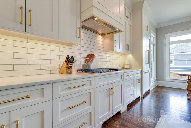 kitchen featuring stainless steel gas stovetop, crown molding, dark wood-style flooring, decorative backsplash, and baseboards