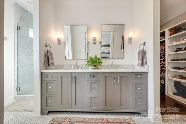 bathroom with double vanity, a stall shower, a spacious closet, and a sink