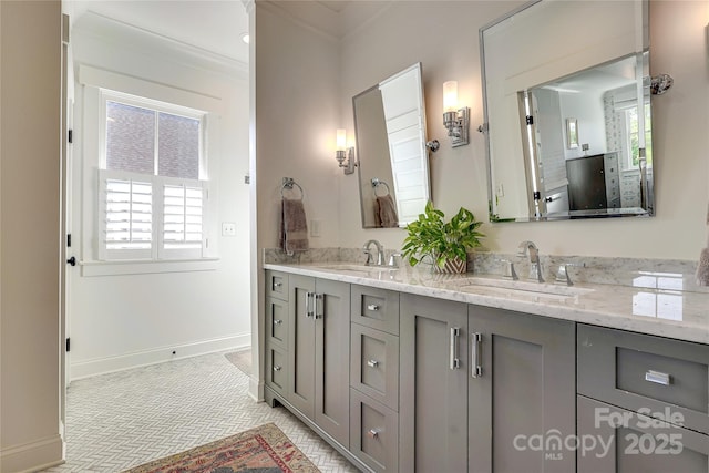 bathroom featuring double vanity, crown molding, baseboards, and a sink