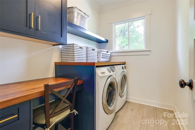 laundry room with washing machine and clothes dryer, baseboards, light wood finished floors, and cabinet space