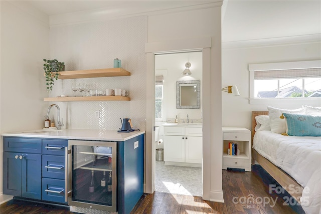 bedroom with ornamental molding, indoor wet bar, a sink, and wine cooler