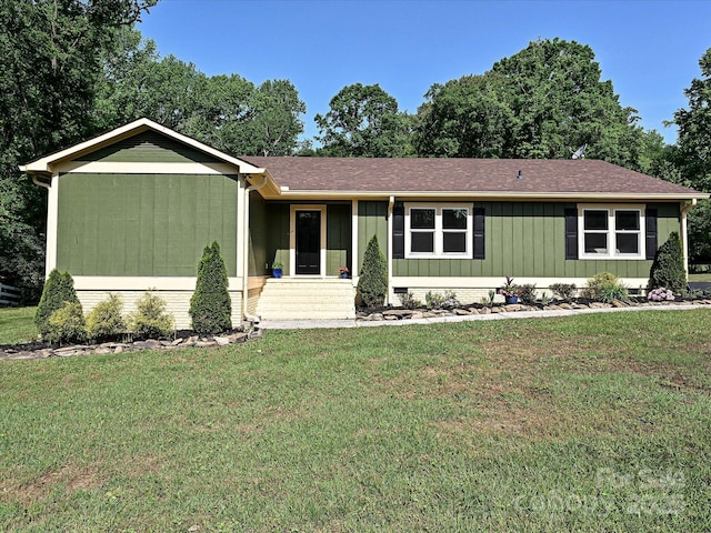 view of front facade with roof with shingles, board and batten siding, and a front yard