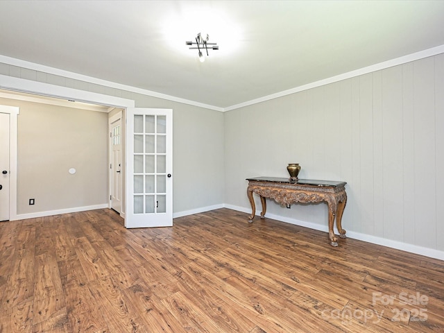 spare room with french doors, ornamental molding, baseboards, and wood finished floors