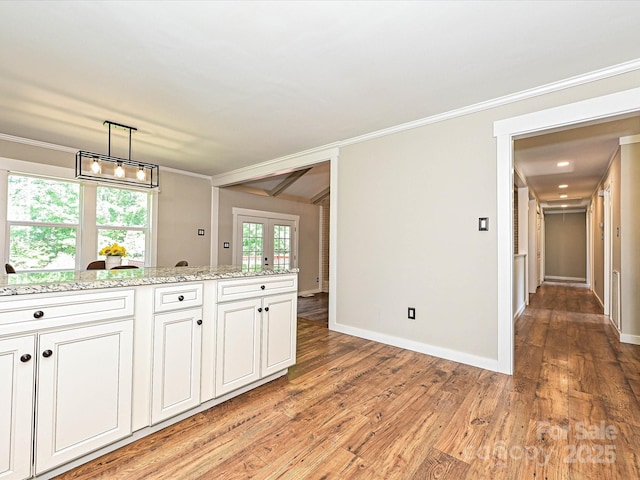 kitchen with ornamental molding, white cabinets, light stone countertops, and light wood-type flooring