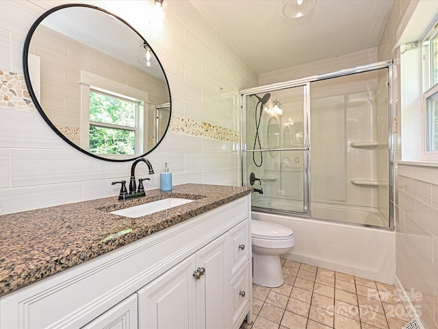 full bathroom featuring vanity, shower / bath combination with glass door, toilet, tile walls, and backsplash