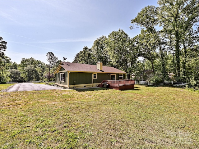 back of property featuring a wooden deck, fence, a chimney, crawl space, and a lawn
