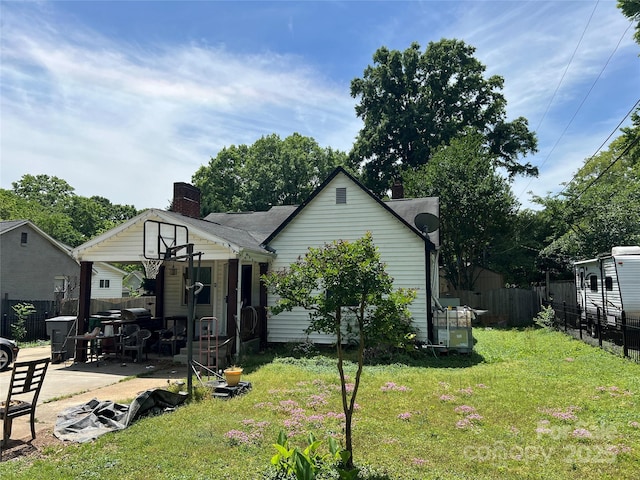 exterior space with a lawn, fence, a chimney, and a patio
