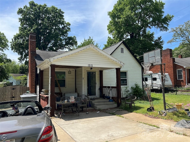 bungalow featuring a porch, fence, and a chimney