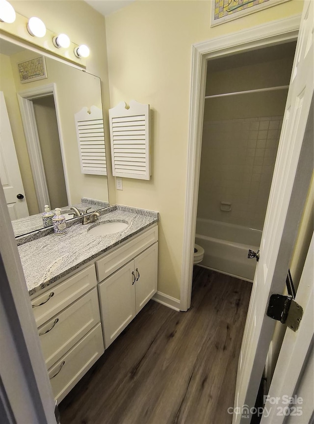 5601 Carmel Station Ave, Charlotte, NC 28226 - bathroom featuring vanity, wood finished floors, washtub / shower combination, toilet, and baseboards