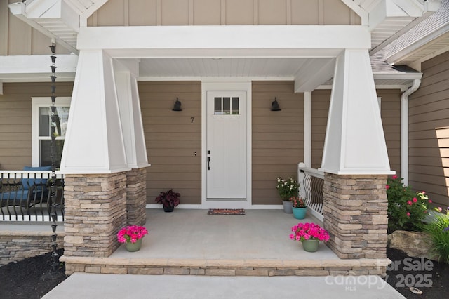 entrance to property with a porch, board and batten siding, and stone siding