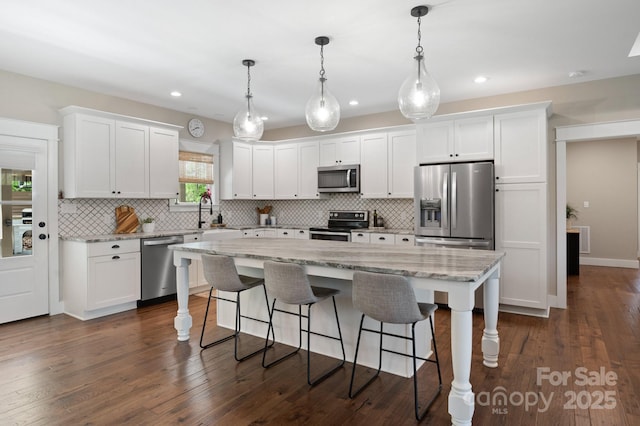kitchen with a sink, appliances with stainless steel finishes, a kitchen island, and tasteful backsplash