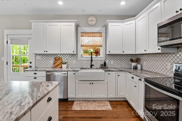 kitchen featuring white cabinets, appliances with stainless steel finishes, a sink, and dark wood-type flooring