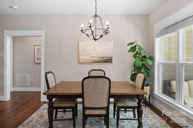 dining area featuring baseboards, visible vents, dark wood-style floors, and an inviting chandelier