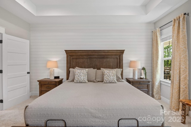 bedroom with a tray ceiling and light colored carpet