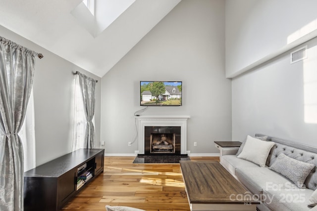 3223 Rheinwood Ct, Matthews, NC 28105 - living room featuring high vaulted ceiling, light wood-style flooring, a fireplace with raised hearth, and baseboards