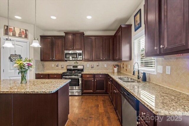 1011 Potomac Rd, Indian Trail, NC 28079 - kitchen featuring stainless steel appliances, dark wood-style floors, light stone countertops, decorative light fixtures, and tasteful backsplash