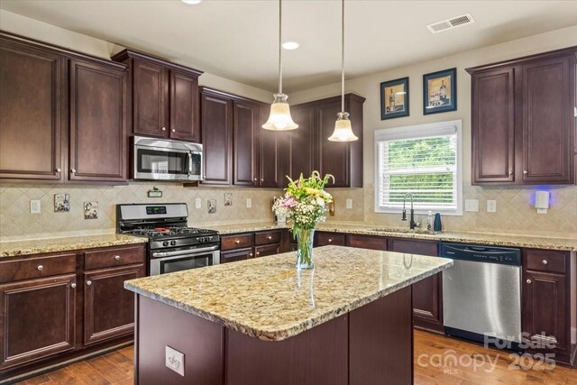 1011 Potomac Rd, Indian Trail, NC 28079 - kitchen with appliances with stainless steel finishes, dark wood-type flooring, a center island, and light stone countertops