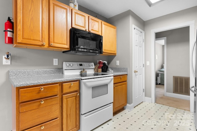 kitchen featuring electric range, black microwave, light countertops, light floors, and visible vents