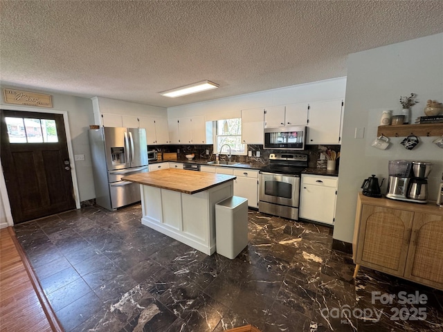 kitchen with a sink, white cabinets, wooden counters, and stainless steel appliances