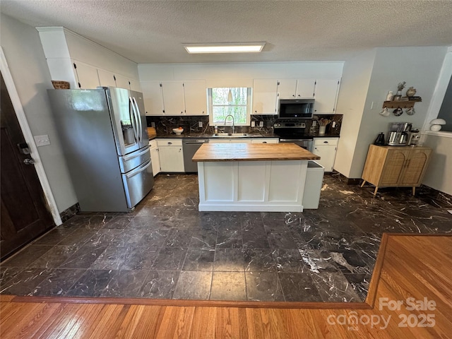 kitchen with white cabinets, backsplash, a textured ceiling, and appliances with stainless steel finishes