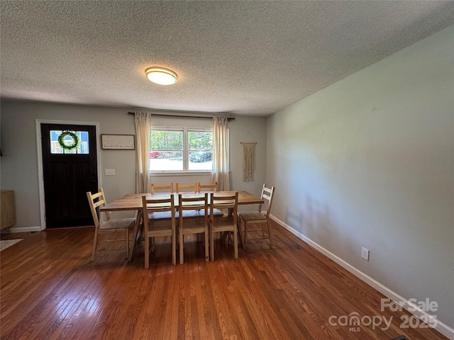 dining room featuring a textured ceiling, baseboards, and wood finished floors