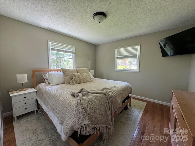 bedroom featuring baseboards, dark wood finished floors, and a textured ceiling