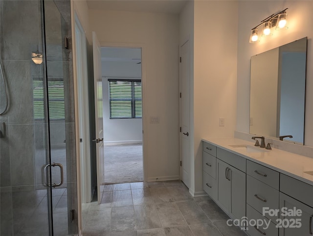 bathroom featuring double vanity, a sink, baseboards, and a stall shower