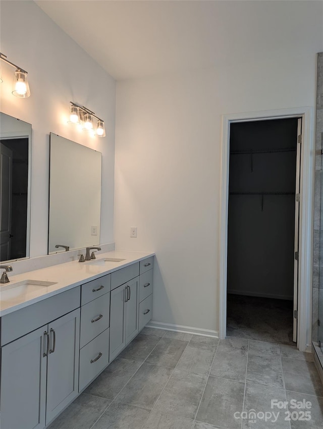 full bath featuring double vanity, a sink, a stall shower, and a spacious closet
