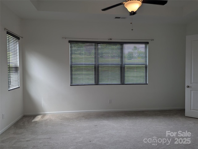 carpeted empty room with baseboards, visible vents, a ceiling fan, and a wealth of natural light