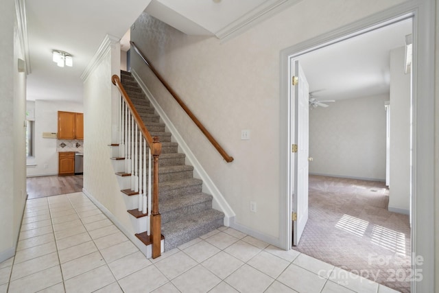 staircase with crown molding, ceiling fan, baseboards, and tile patterned flooring