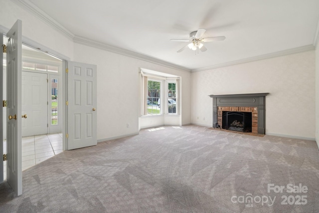 unfurnished living room featuring ceiling fan, a brick fireplace, baseboards, ornamental molding, and carpet flooring