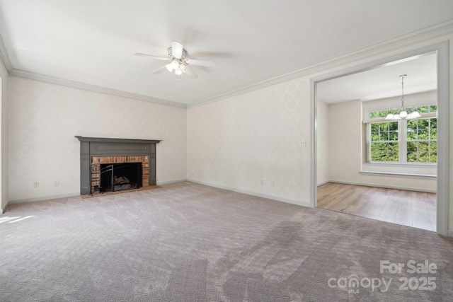 unfurnished living room featuring crown molding, carpet, ceiling fan with notable chandelier, and a fireplace