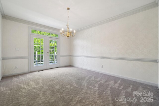 unfurnished room with an inviting chandelier, carpet floors, crown molding, and baseboards