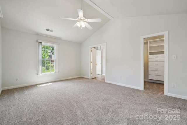 unfurnished bedroom with carpet flooring, visible vents, baseboards, lofted ceiling, and a spacious closet