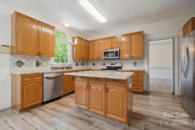 kitchen with light wood-style floors, appliances with stainless steel finishes, decorative backsplash, and a center island