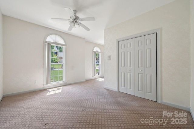 unfurnished bedroom featuring carpet flooring, a ceiling fan, baseboards, and a closet