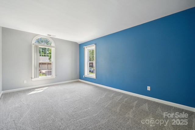 empty room featuring carpet flooring, baseboards, and visible vents