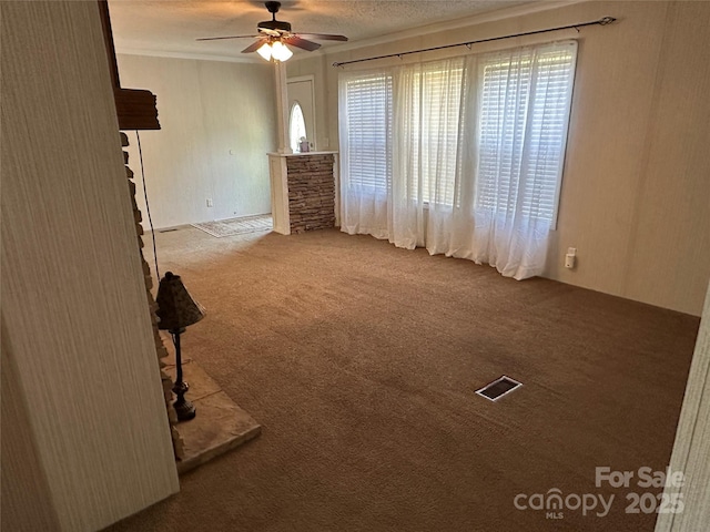 empty room featuring plenty of natural light, a ceiling fan, carpet flooring, and visible vents
