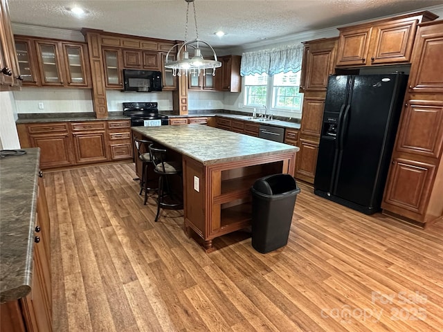 kitchen featuring light wood-type flooring, a textured ceiling, a kitchen island, and black appliances