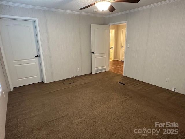 unfurnished bedroom with crown molding, carpet, a ceiling fan, and visible vents