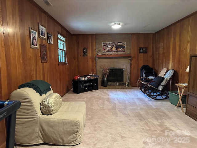 living area with wooden walls, visible vents, light carpet, and a brick fireplace
