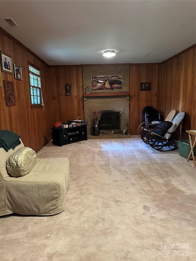 carpeted living area featuring a brick fireplace, wood walls, and visible vents