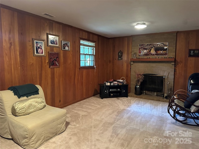 carpeted living room with wooden walls, ornamental molding, a fireplace, and visible vents