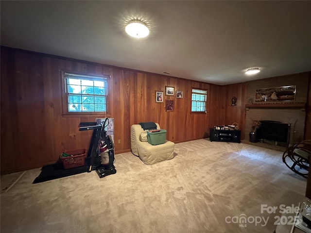 sitting room featuring a brick fireplace, wooden walls, and carpet flooring