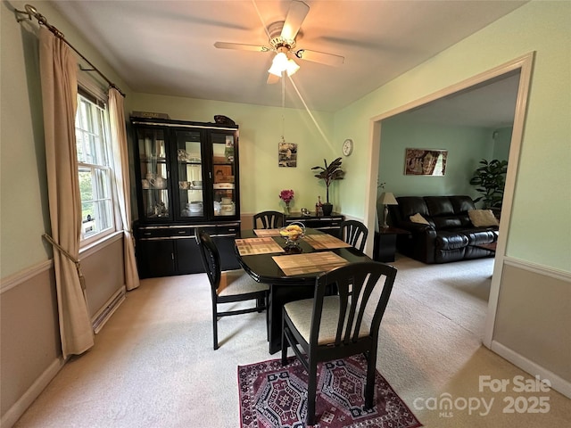 dining area featuring baseboards, ceiling fan, and light colored carpet